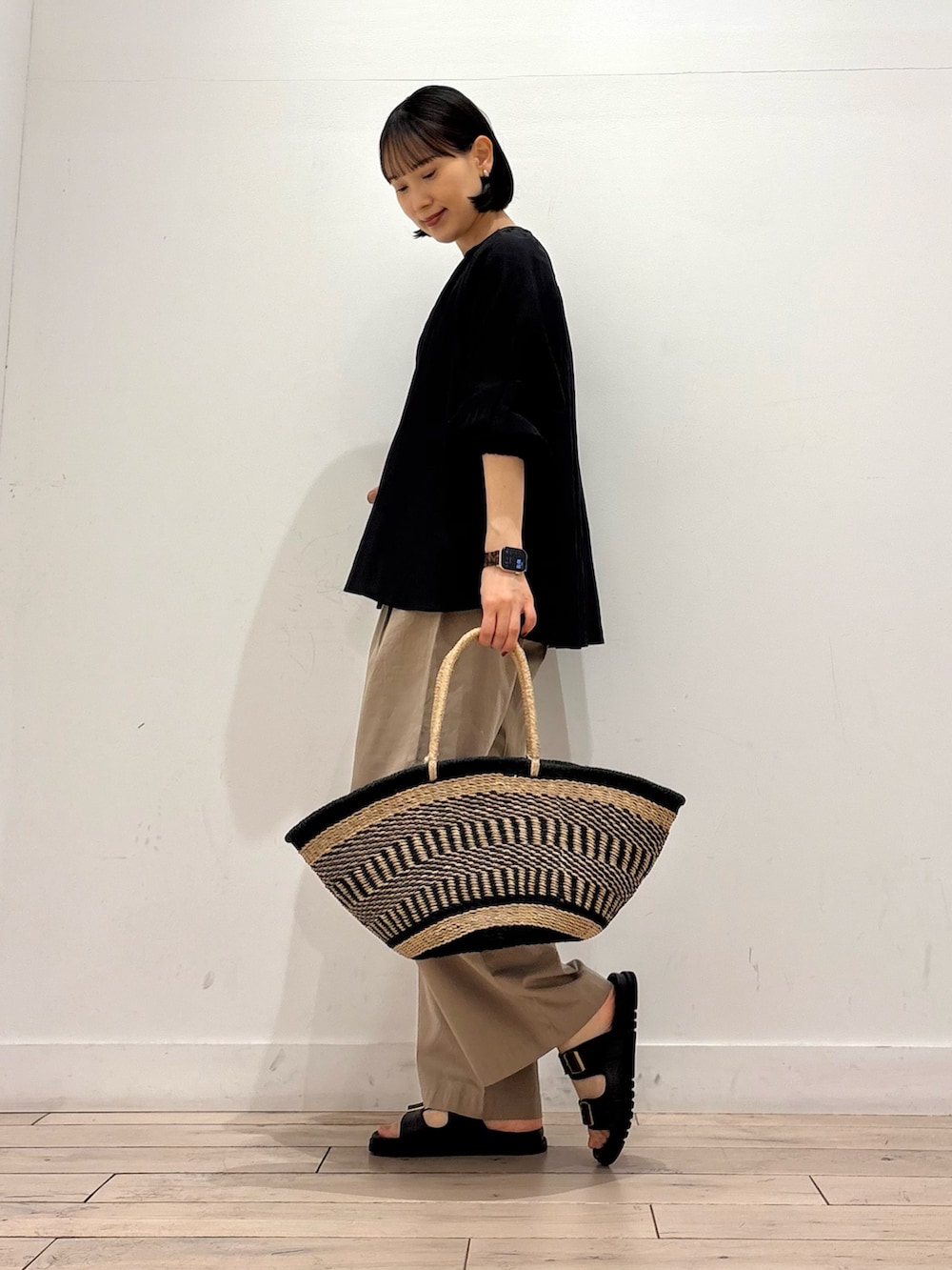 ブラック系のシャツ/ブラウス、ベージュ系のその他パンツ、ブラック系のかごバッグを着用したレディースの春コーディネートの2枚目の写真