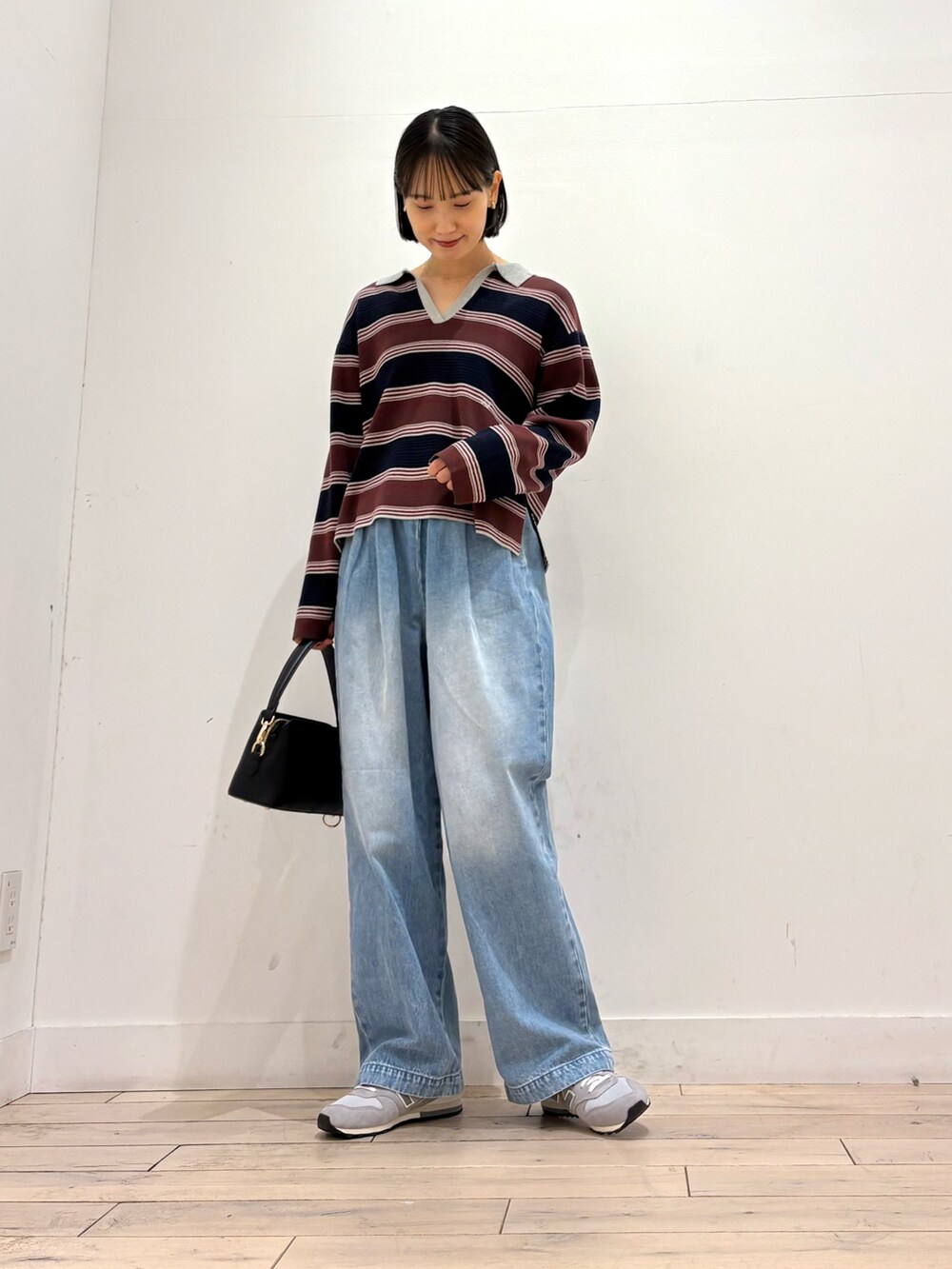 ブルー系のニット/セーター、ブルー系のデニムパンツ、ブラック系のショルダーバッグを着用したレディースの秋コーディネートの2枚目の写真