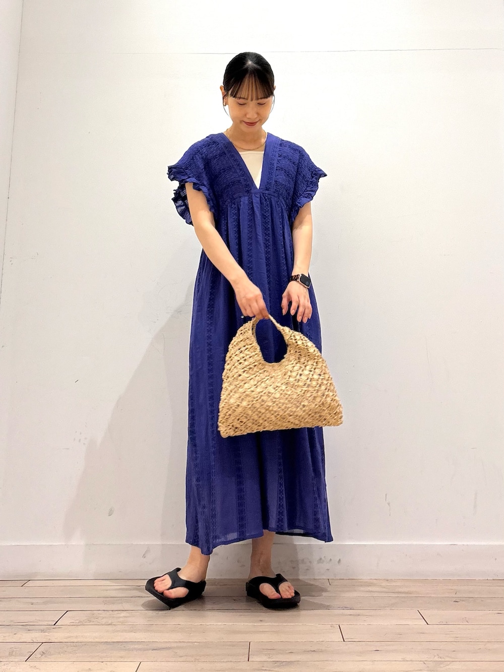 ブルー系のワンピース、ベージュ系のハンドバッグ、ブラック系のサンダルを着用したレディースの夏コーディネートの2枚目の写真