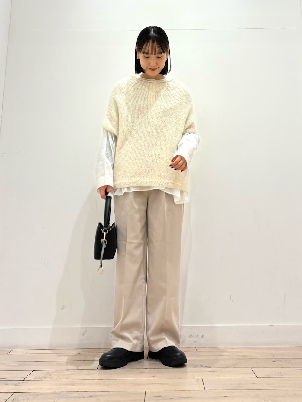 ホワイト系のニット/セーター、ホワイト系のシャツ/ブラウス、ブラック系のブーツを着用したレディースの冬コーディネートの2枚目の写真