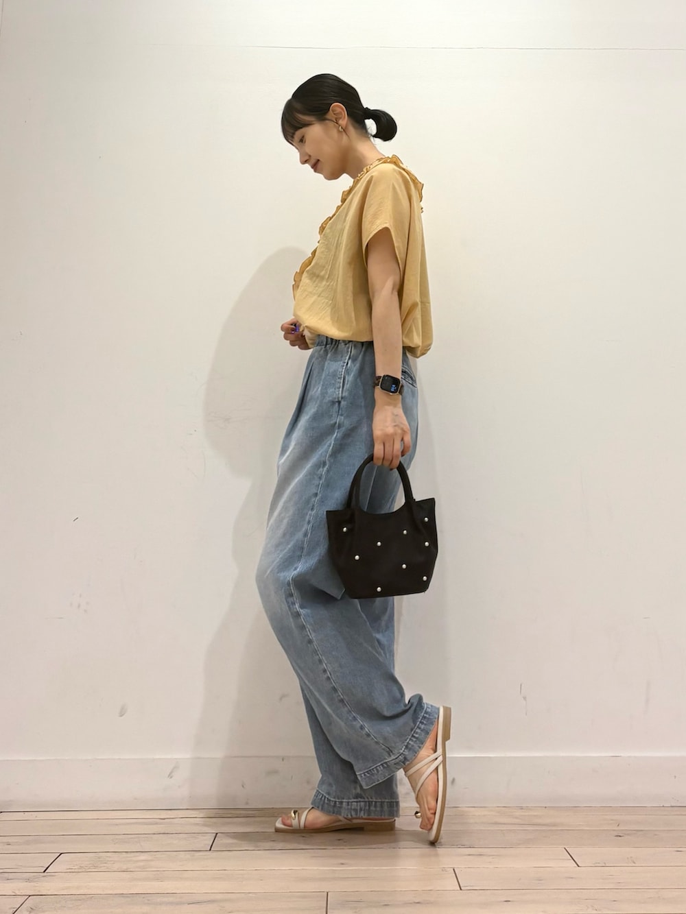 ブルー系のデニムパンツ、グレー系のサンダル、イエロー系のシャツ/ブラウスを着用したレディースの夏コーディネートの2枚目の写真