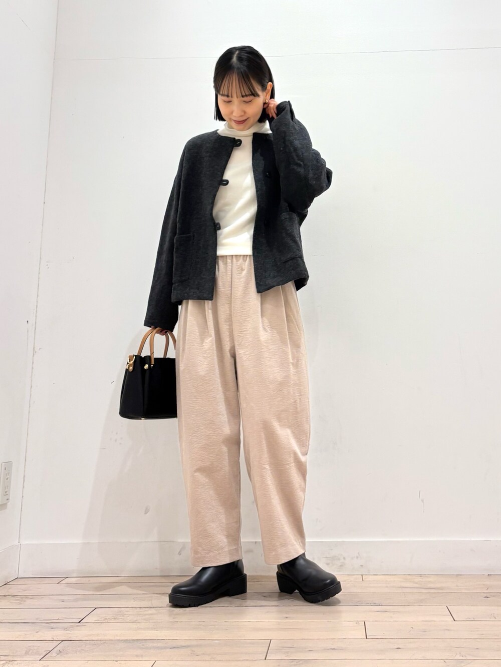 グレー系のノーカラージャケット、ホワイト系のTシャツ/カットソー、ブラック系のブーツを着用したレディースの秋コーディネートの3枚目の写真