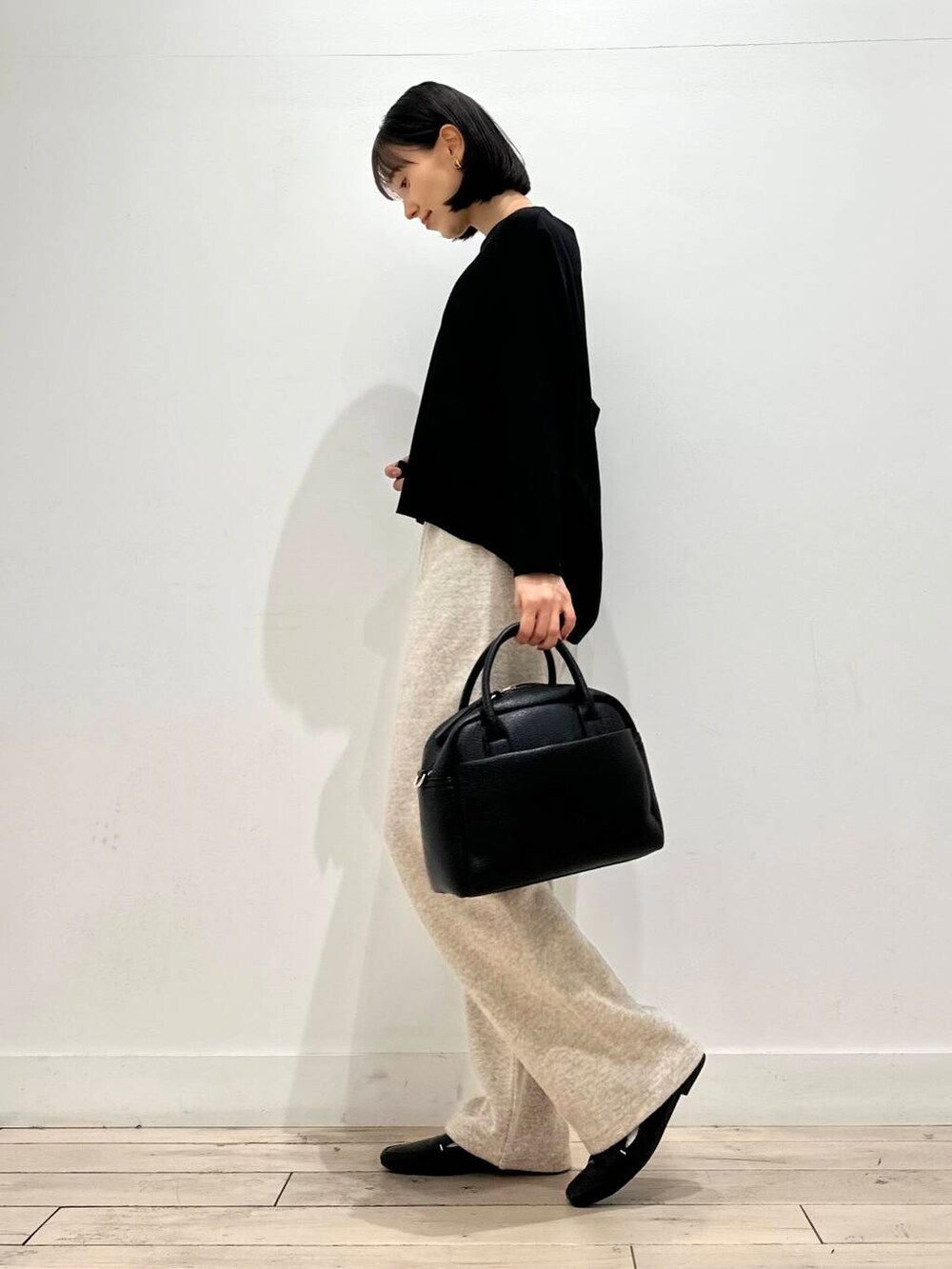 ブラック系のローファー、ブラック系のTシャツ/カットソー、ブラック系のボストンバッグを着用したレディースの秋コーディネートの2枚目の写真