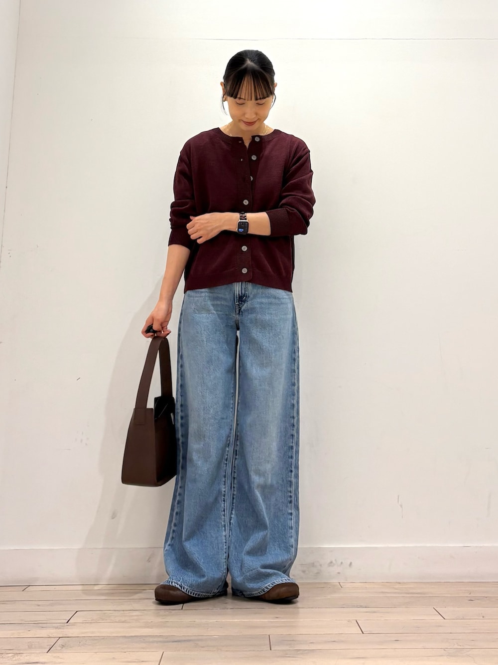 レッド系のカーディガン/ボレロ、ブルー系のデニムパンツ、ブラウン系のハンドバッグを着用したレディースの秋コーディネートの3枚目の写真