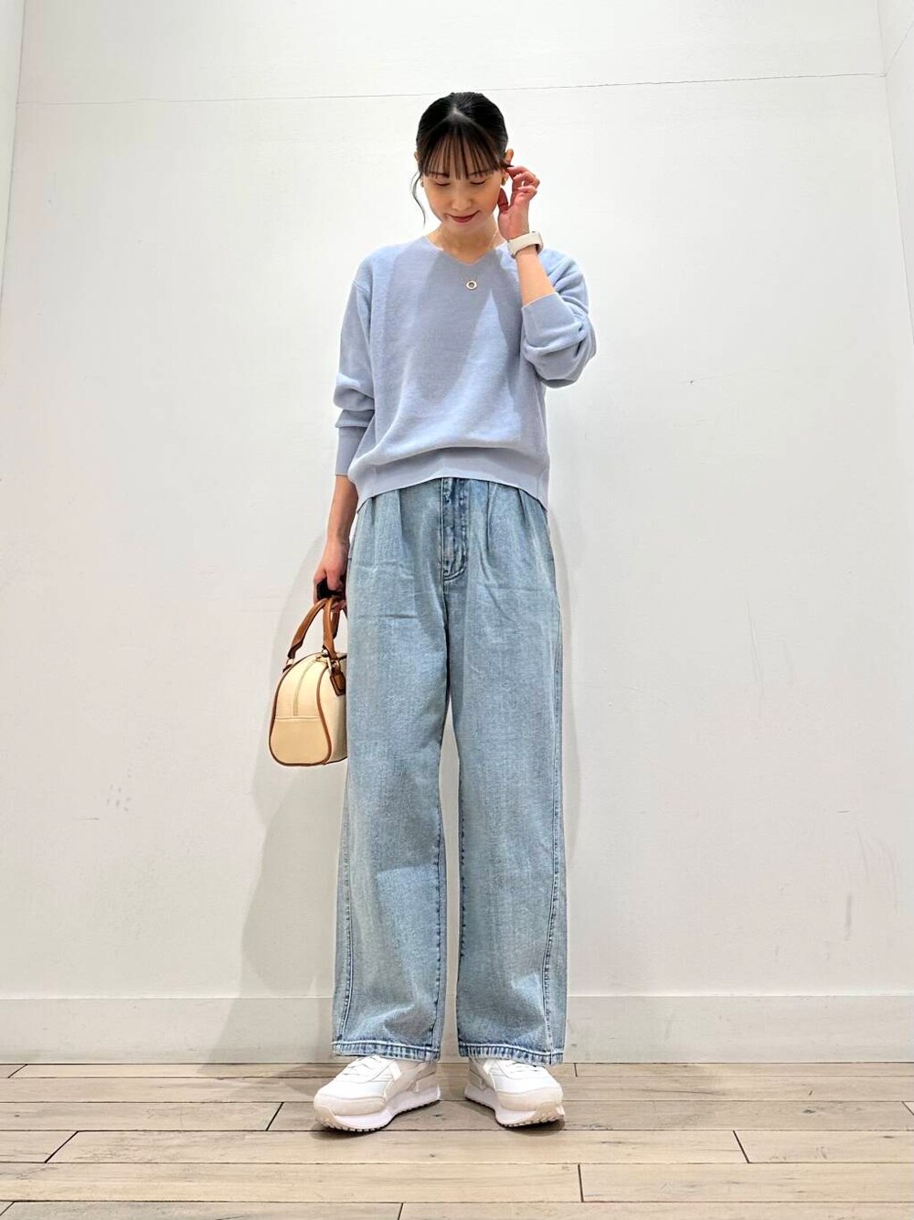 ブルー系のデニムパンツ、ベージュ系のその他アウター、イエロー系のボストンバッグを着用したレディースの冬コーディネートの4枚目の写真