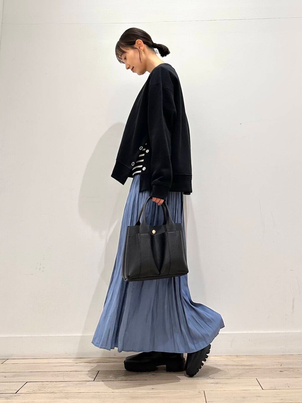 ブラック系のトートバッグ、ホワイト系のTシャツ/カットソー、ブラック系のブーツを着用したレディースの冬コーディネートの3枚目の写真