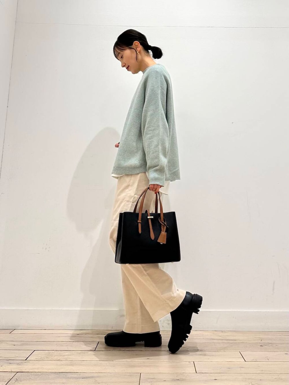 ブラック系のトートバッグ、グリーン系のニット/セーター、ブラック系のブーツを着用したレディースの冬コーディネートの3枚目の写真