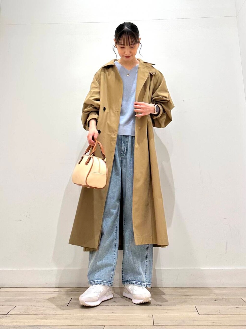 ブルー系のデニムパンツ、ベージュ系のその他アウター、イエロー系のボストンバッグを着用したレディースの冬コーディネートの2枚目の写真