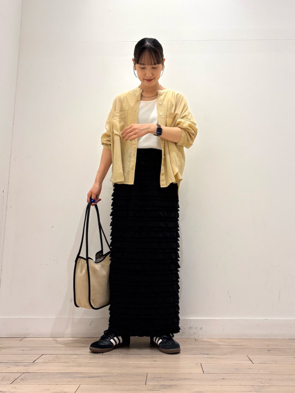 イエロー系のシャツ/ブラウス、ブラック系のスカート、ベージュ系のトートバッグを着用したレディースの夏コーディネートの4枚目の写真