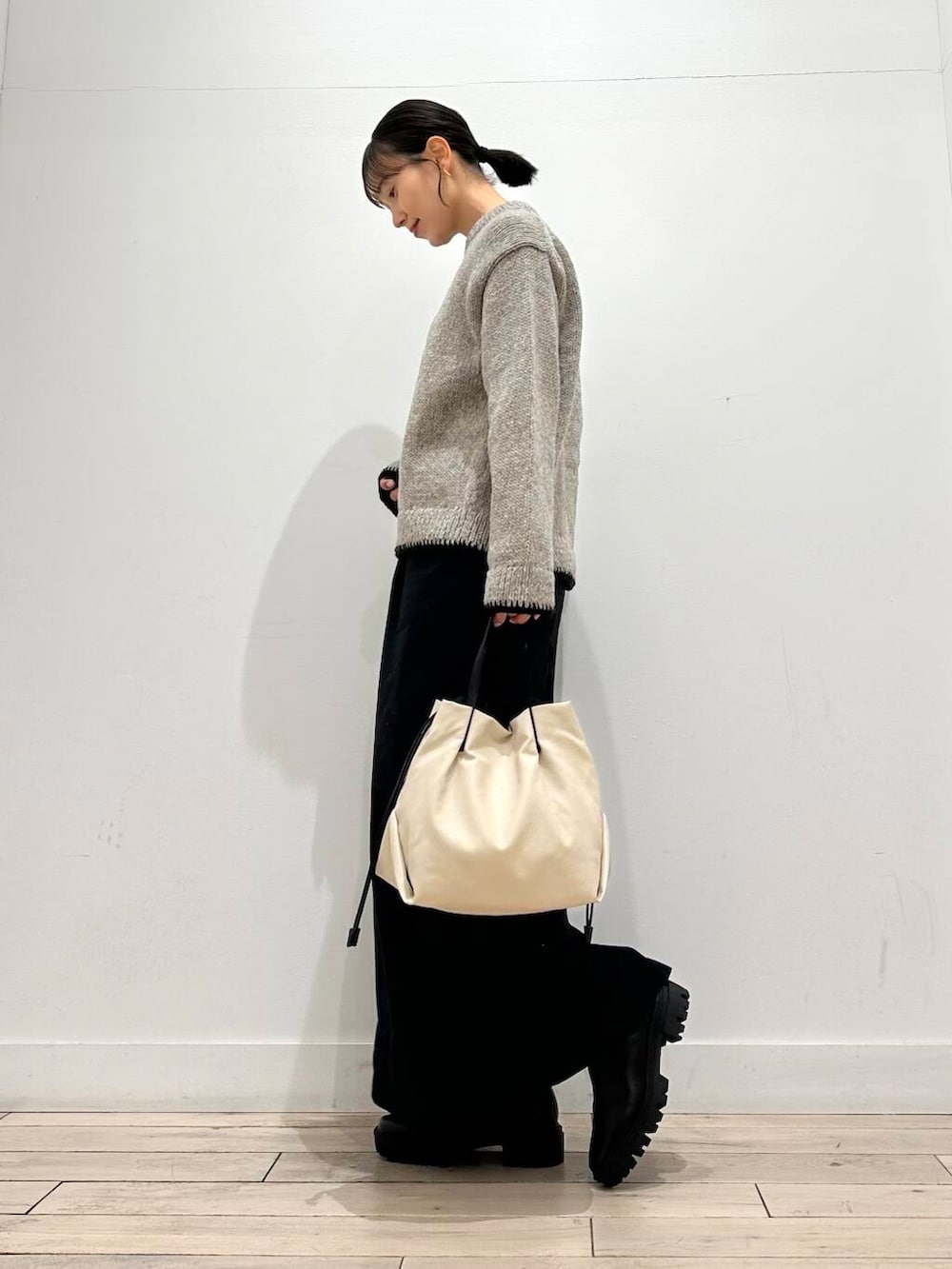ホワイト系のショルダーバッグ、グレー系のニット/セーター、ブラック系のスカートを着用したレディースの冬コーディネートの3枚目の写真