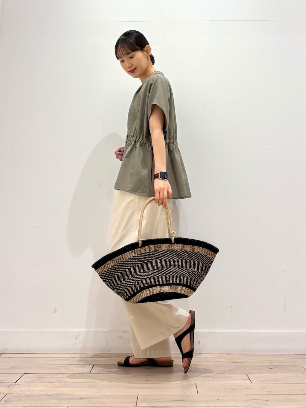 ホワイト系のその他パンツ、ブラック系のかごバッグ、ブラック系のサンダルを着用したレディースの夏コーディネートの3枚目の写真