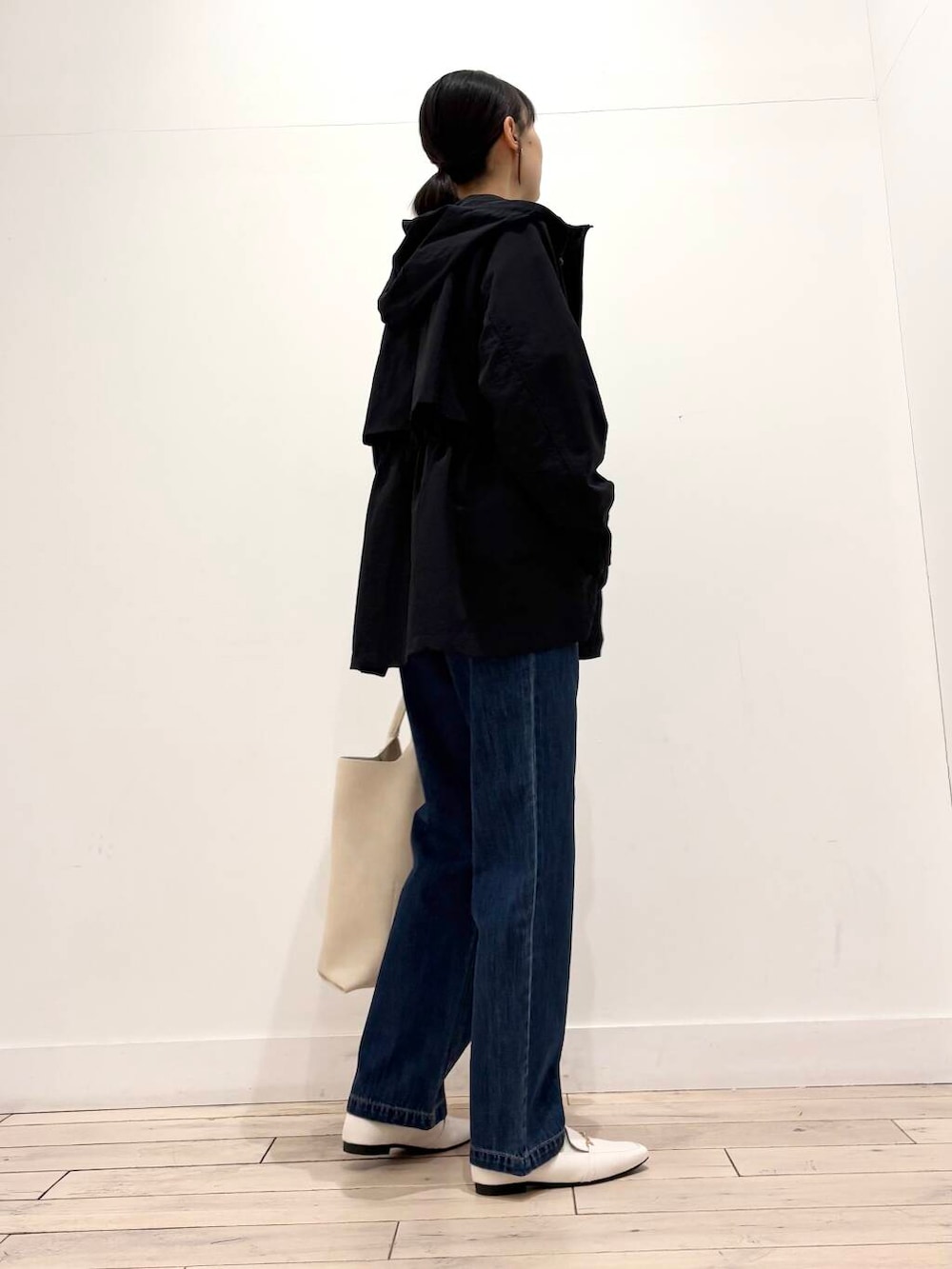 ブルー系のデニムパンツ、ブラック系のマウンテンパーカー、ホワイト系のローファーを着用したレディースの春コーディネートの3枚目の写真