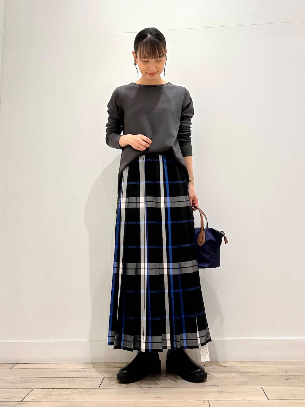 ブルー系のトートバッグ、ブラック系のブーツ、ブラック系のスカートを着用したレディースの夏コーディネートの2枚目の写真