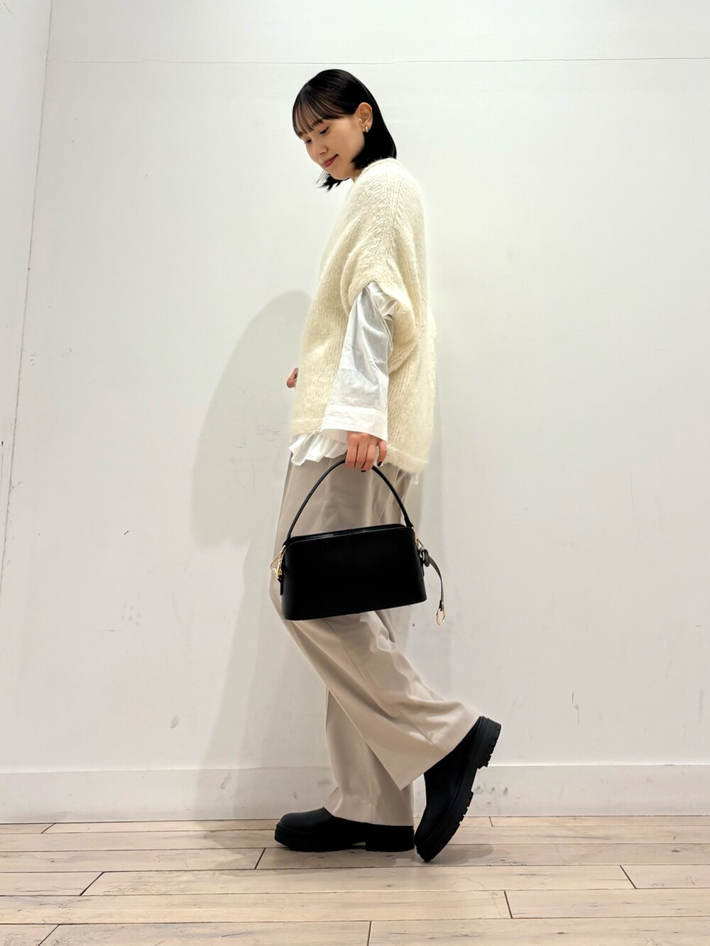 ホワイト系のニット/セーター、ホワイト系のシャツ/ブラウス、ブラック系のブーツを着用したレディースの冬コーディネートの3枚目の写真