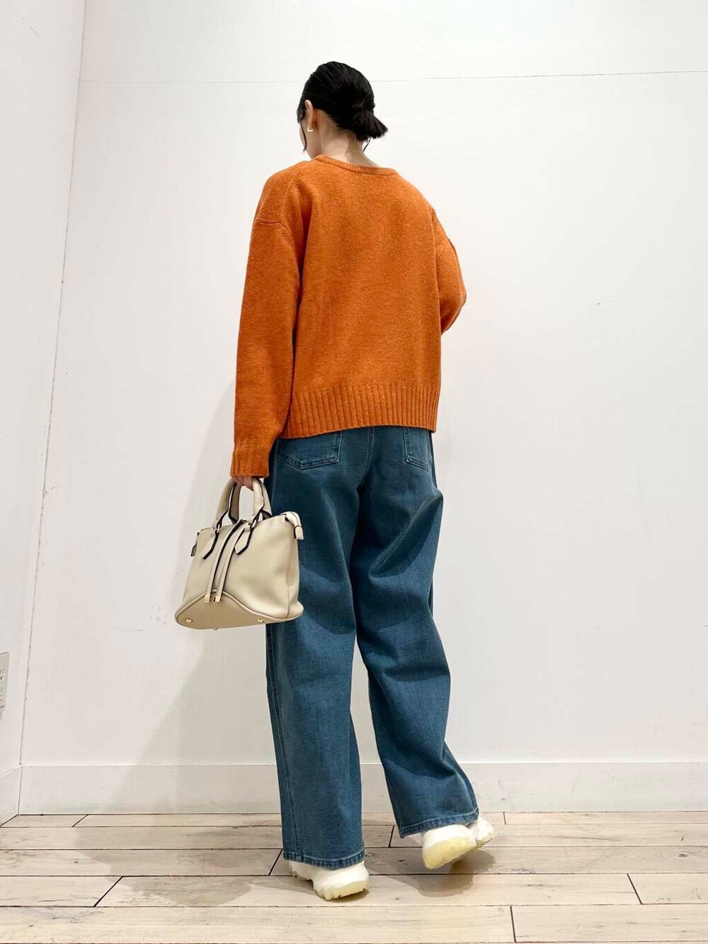 ホワイト系のスニーカー、オレンジ系のニット/セーター、ホワイト系のボストンバッグを着用したレディースの冬コーディネートの5枚目の写真