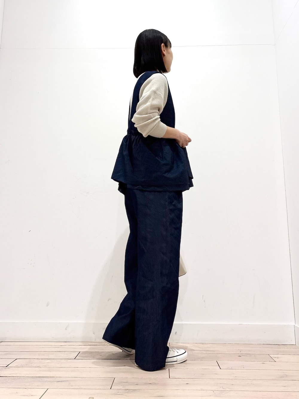 グレー系のニット/セーター、ホワイト系のスニーカー、ホワイト系のショルダーバッグを着用したレディースの春コーディネートの3枚目の写真