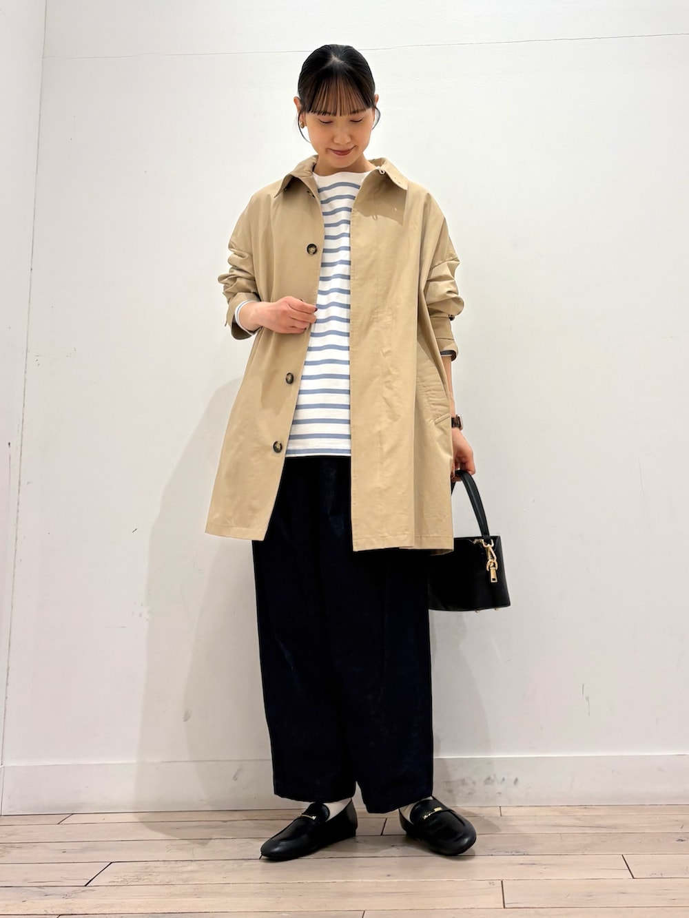 ブルー系のTシャツ/カットソー、ベージュ系のステンカラーコート、ブルー系のデニムパンツを着用したレディースの春コーディネートの2枚目の写真