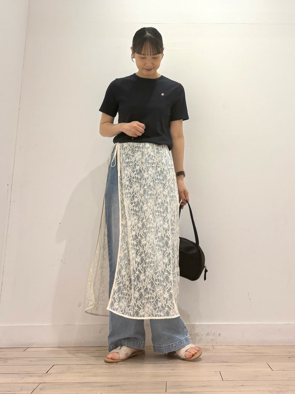 ホワイト系のスカート、ブラック系のボストンバッグ、ホワイト系のサンダルを着用したレディースの夏コーディネートの2枚目の写真