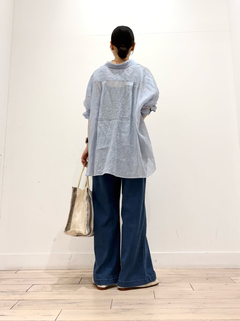 ブルー系のデニムパンツ、ホワイト系のトートバッグ、ホワイト系のバレエシューズを着用したレディースの夏コーディネートの4枚目の写真