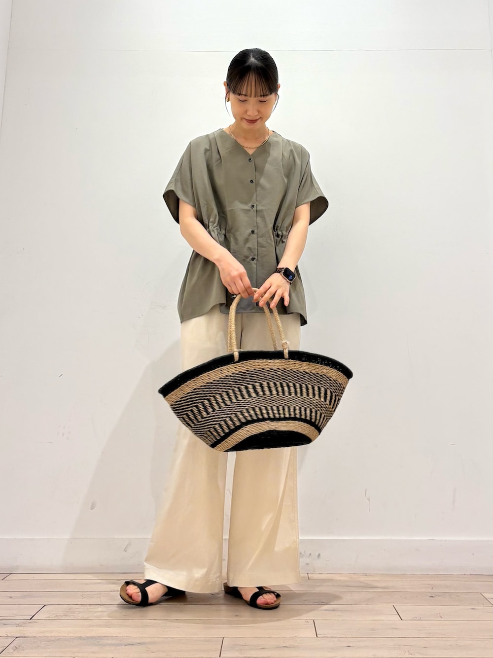 ホワイト系のその他パンツ、ブラック系のかごバッグ、ブラック系のサンダルを着用したレディースの夏コーディネートの2枚目の写真