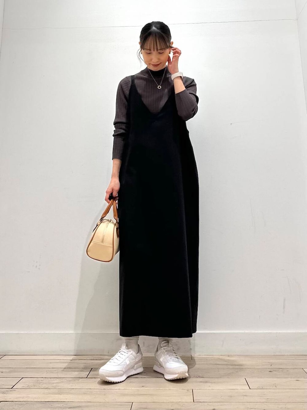 ブラウン系のニット/セーター、ホワイト系のダウンジャケット/コート、イエロー系のボストンバッグを着用したレディースの冬コーディネートの2枚目の写真