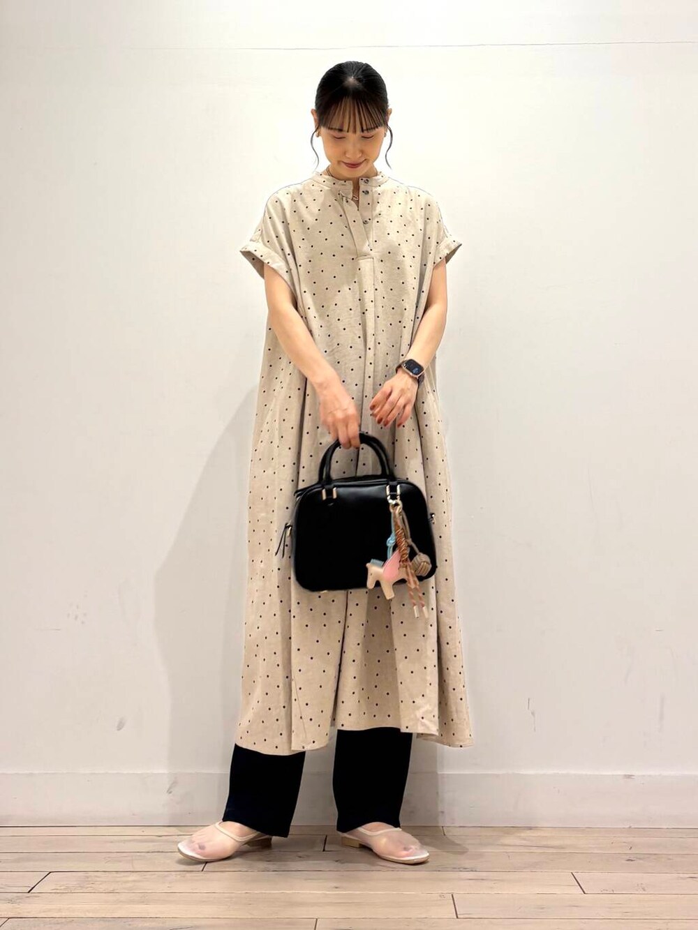 ブルー系のデニムパンツ、ホワイト系のバレエシューズ、ブラック系のボストンバッグを着用したレディースの夏コーディネートの2枚目の写真