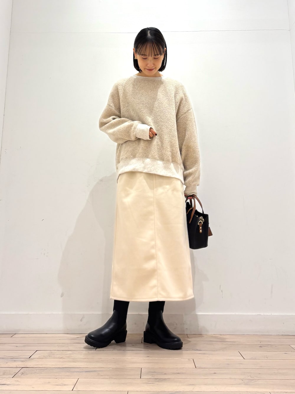 ブラック系のブーツ、ブラック系のハンドバッグ、ホワイト系のスカートを着用したレディースの冬コーディネートの5枚目の写真