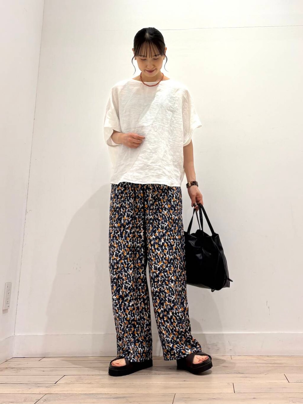 ブラック系のショルダーバッグ、ブラウン系のサンダル、ホワイト系のシャツ/ブラウスを着用したレディースの夏コーディネートの2枚目の写真