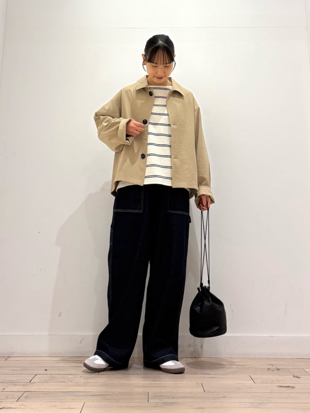ベージュ系のステンカラーコート、ホワイト系のTシャツ/カットソー、ブルー系のデニムパンツを着用したレディースの秋コーディネートの2枚目の写真