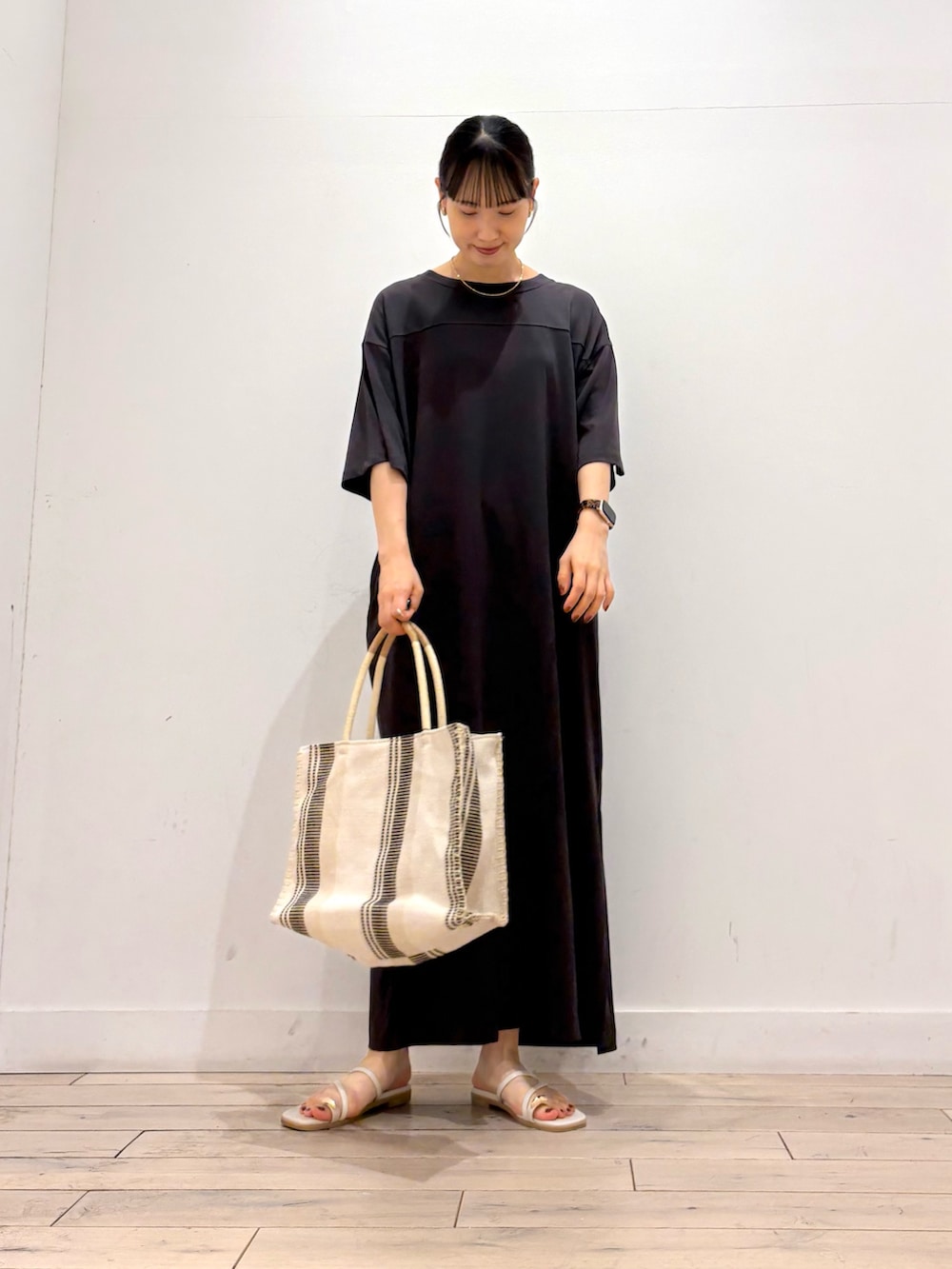 グレー系のワンピース、ホワイト系のトートバッグ、グレー系のサンダルを着用したレディースの夏コーディネートの2枚目の写真