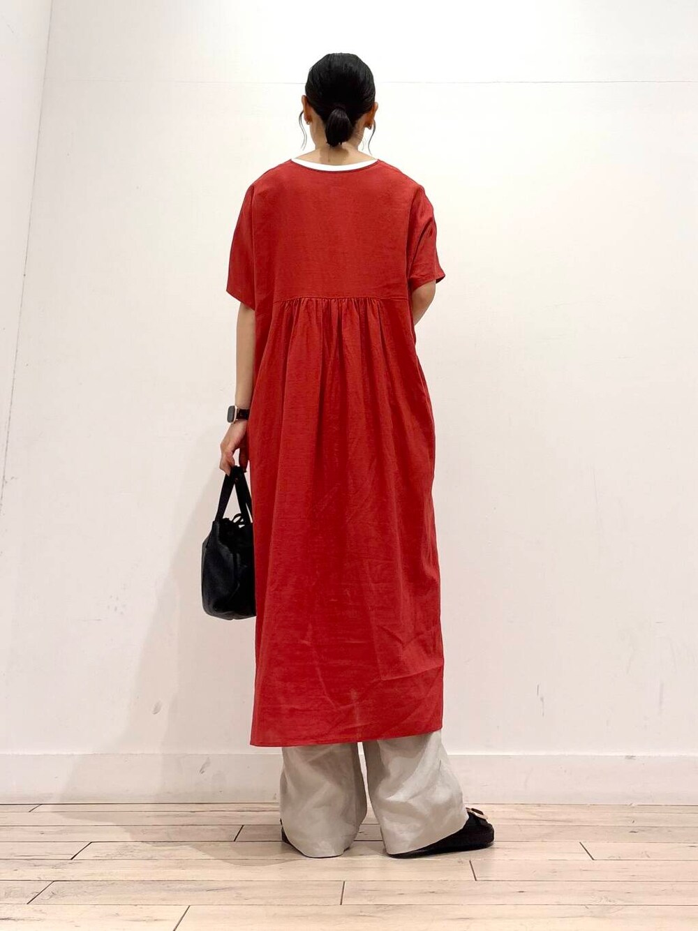 ブラック系のショルダーバッグ、ブラック系のサンダル、レッド系のワンピースを着用したレディースの夏コーディネートの5枚目の写真