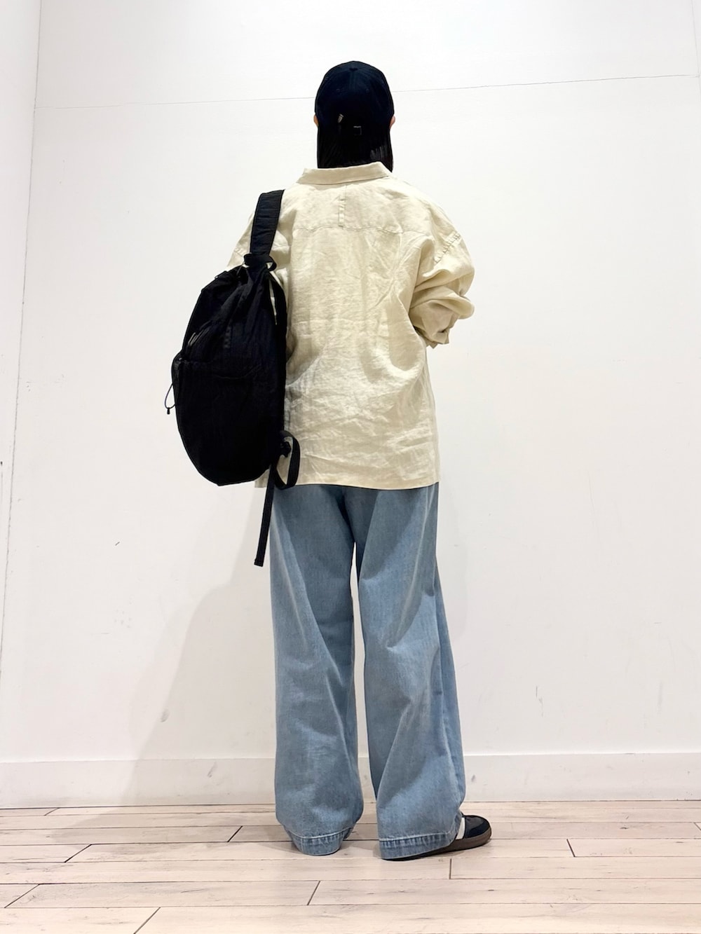 ブルー系のデニムパンツ、ブラック系のスニーカー、ブラック系のバックパック/リュックを着用したレディースの春コーディネートの4枚目の写真