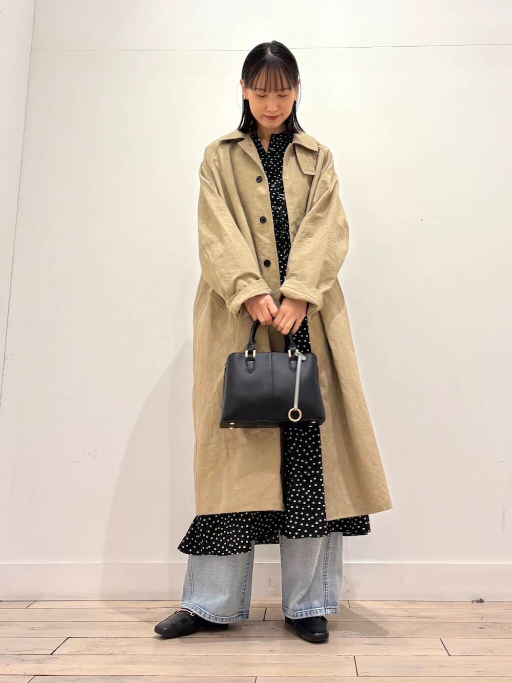 ブラック系のハンドバッグ、ブルー系のデニムパンツ、ブラック系のワンピースを着用したレディースの春コーディネートの5枚目の写真