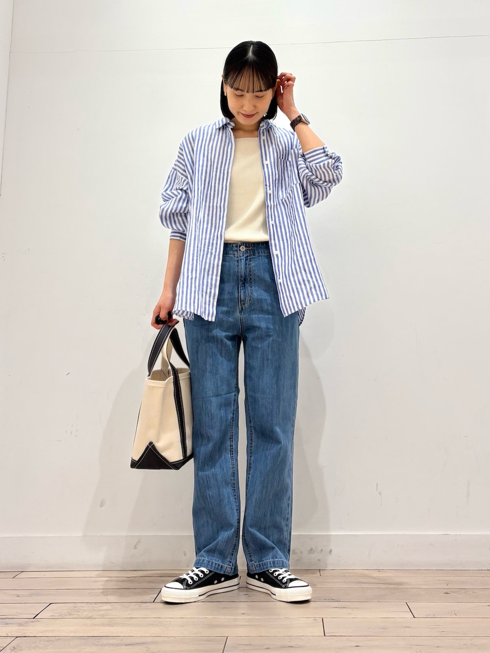 ホワイト系のタンクトップ、グレー系のトートバッグ、ブラック系のスニーカーを着用したレディースの春コーディネートの2枚目の写真