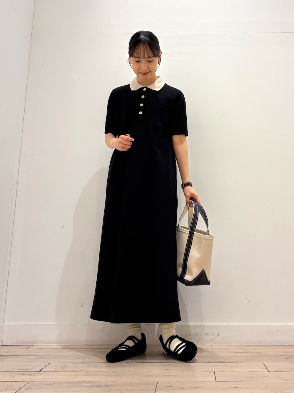 ブラック系のワンピース、グレー系のトートバッグ、ブラック系のスニーカーを着用したレディースの春コーディネートの4枚目の写真