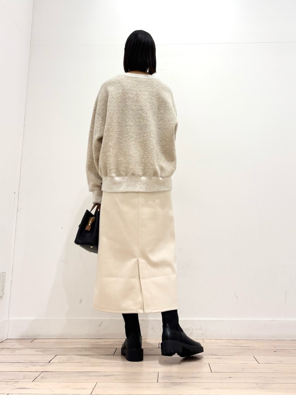 ブラック系のブーツ、ブラック系のハンドバッグ、ホワイト系のスカートを着用したレディースの冬コーディネートの7枚目の写真