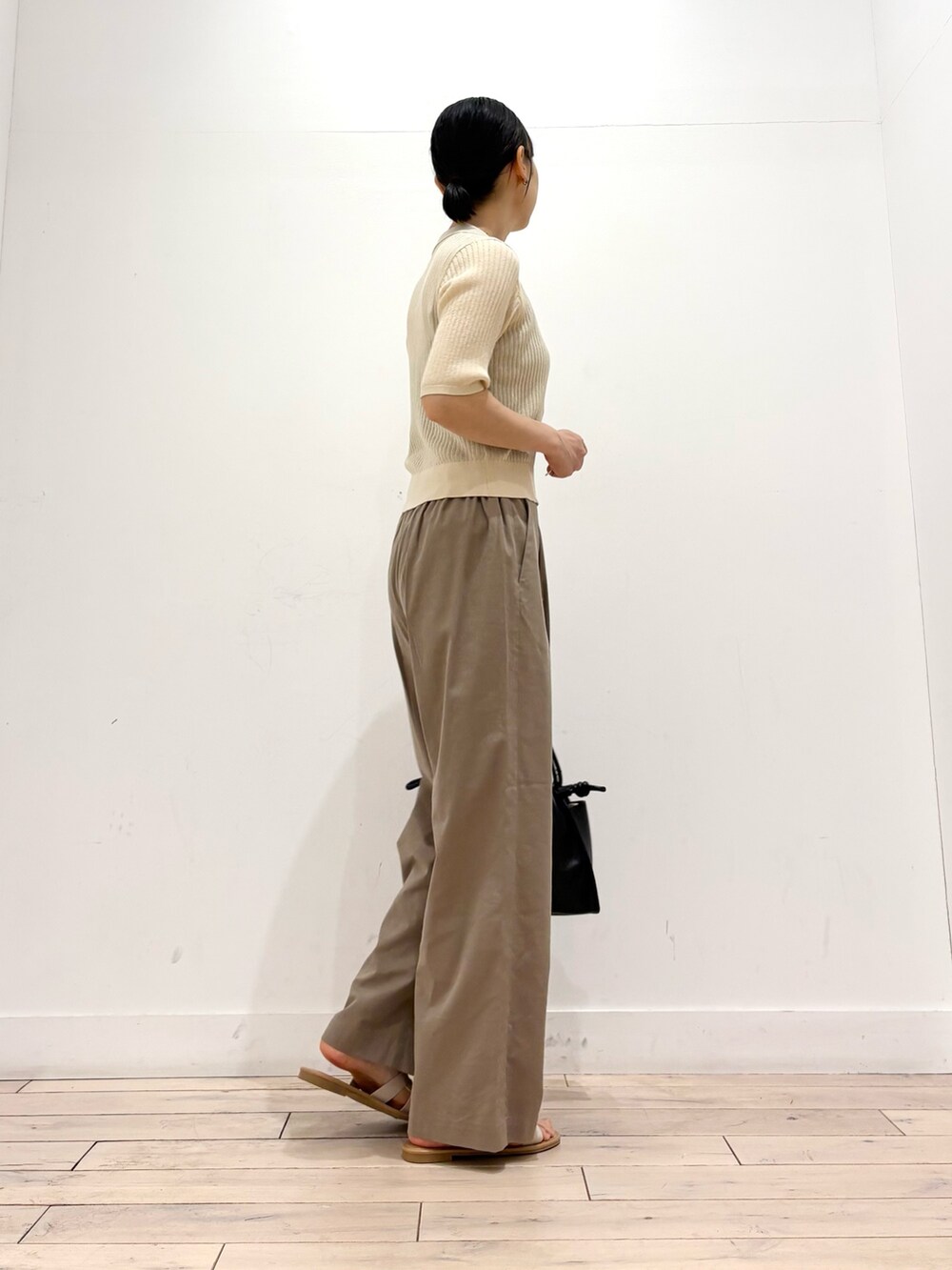 ホワイト系のニット/セーター、ベージュ系のその他パンツ、ブラック系のトートバッグを着用したレディースの夏コーディネートの4枚目の写真