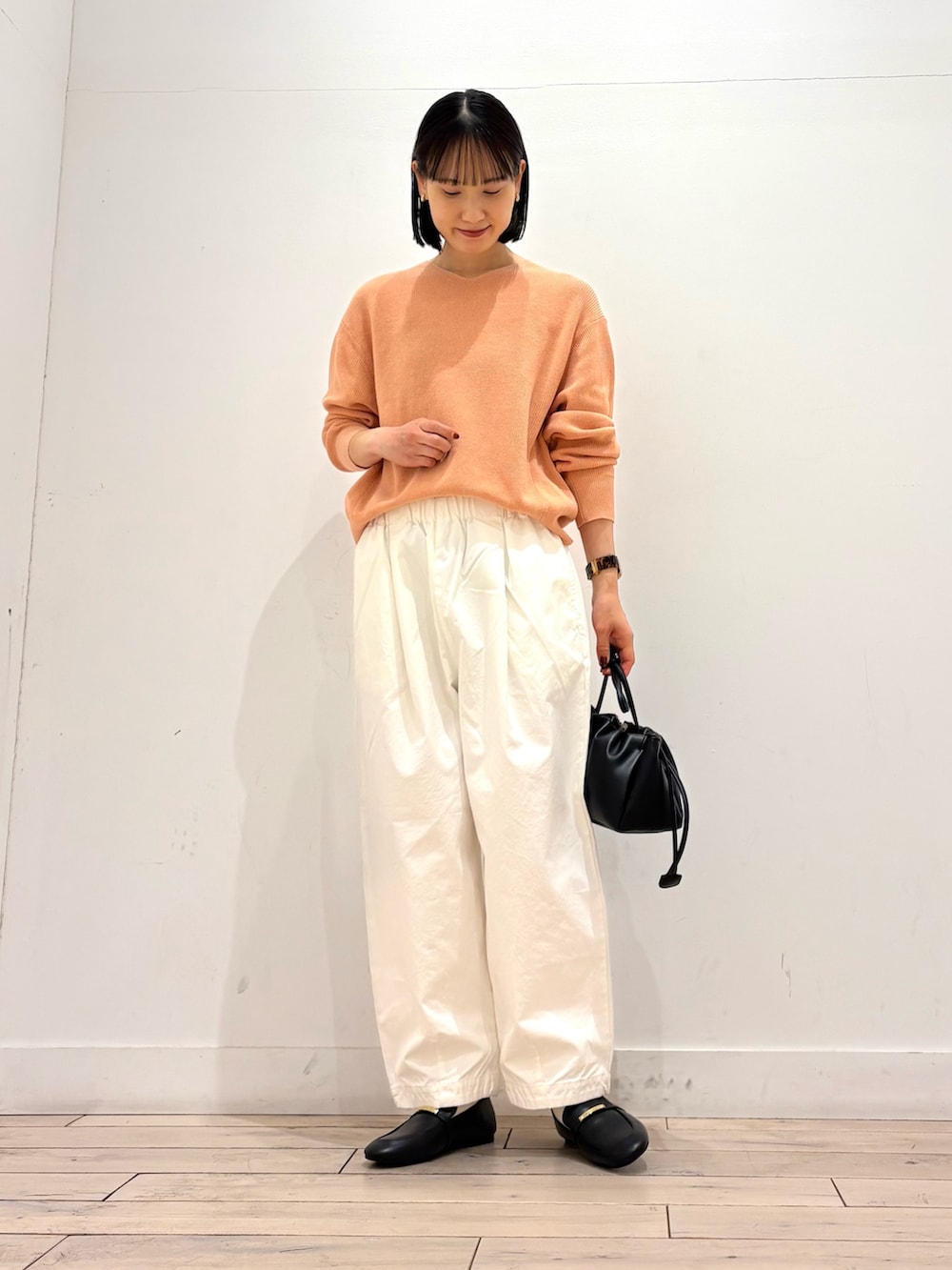 ピンク系のニット/セーター、ホワイト系のその他パンツ、ブラック系のショルダーバッグを着用したレディースの春コーディネートの2枚目の写真