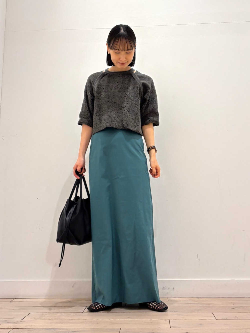 グレー系のニット/セーター、グリーン系のスカート、ブラック系のショルダーバッグを着用したレディースの春コーディネートの3枚目の写真