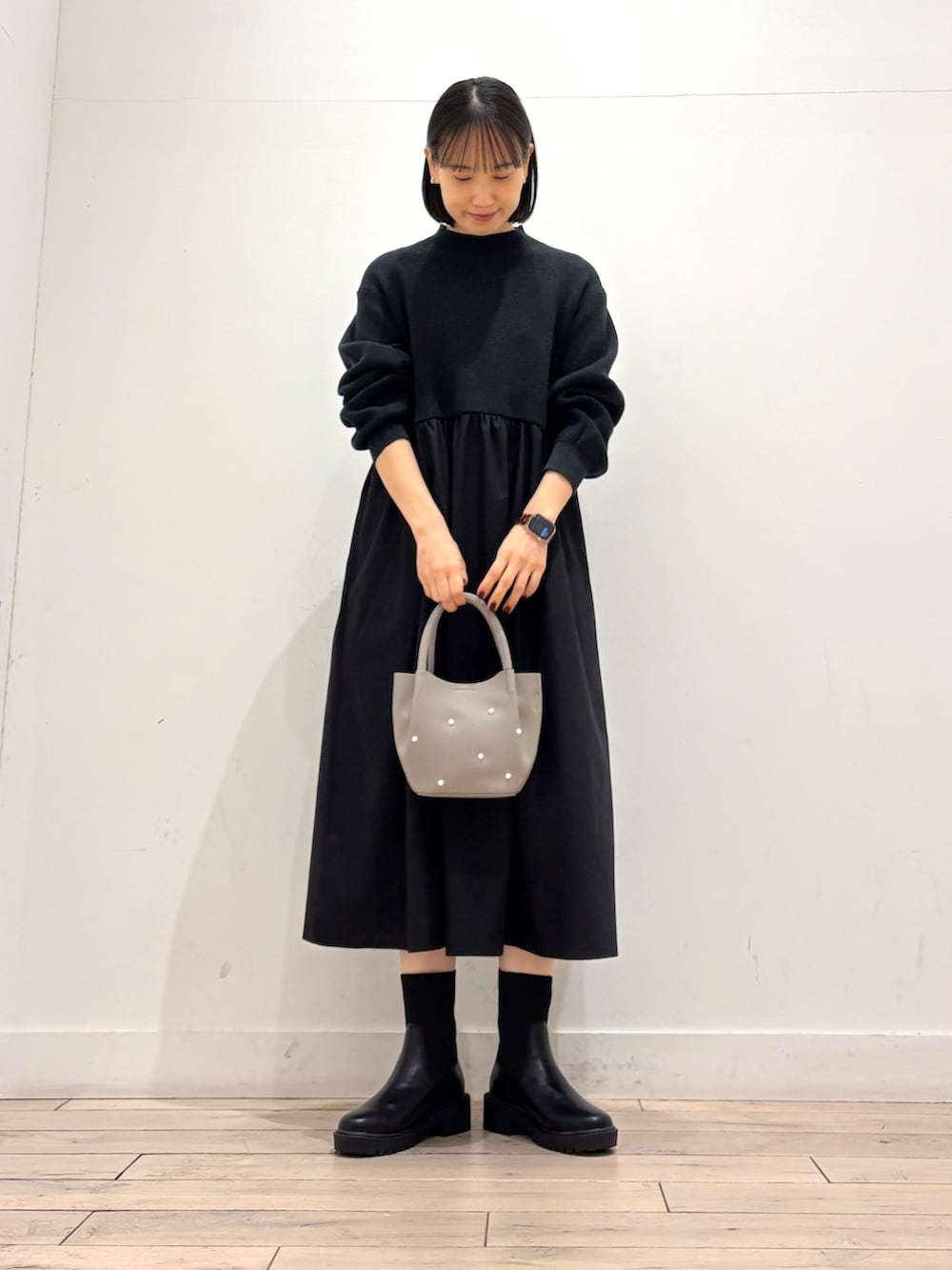 ブラック系のワンピース、グレー系のハンドバッグ、ブラック系のブーツを着用したレディースの秋コーディネートの2枚目の写真