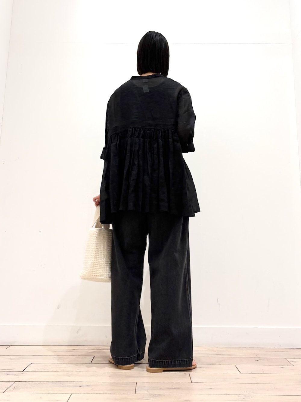 ブラック系のデニムパンツ、ホワイト系のトートバッグ、ホワイト系のサンダルを着用したレディースの春コーディネートの6枚目の写真