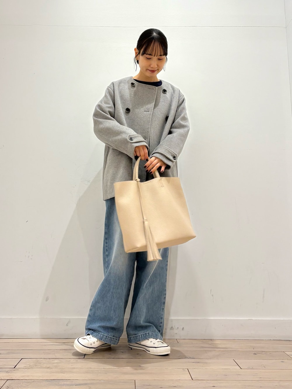 グレー系のピーコート、ブルー系のデニムパンツ、ホワイト系のトートバッグを着用したレディースの冬コーディネートの2枚目の写真