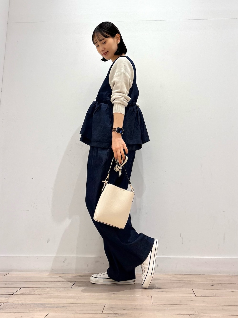 グレー系のニット/セーター、ホワイト系のスニーカー、ホワイト系のショルダーバッグを着用したレディースの春コーディネートの2枚目の写真