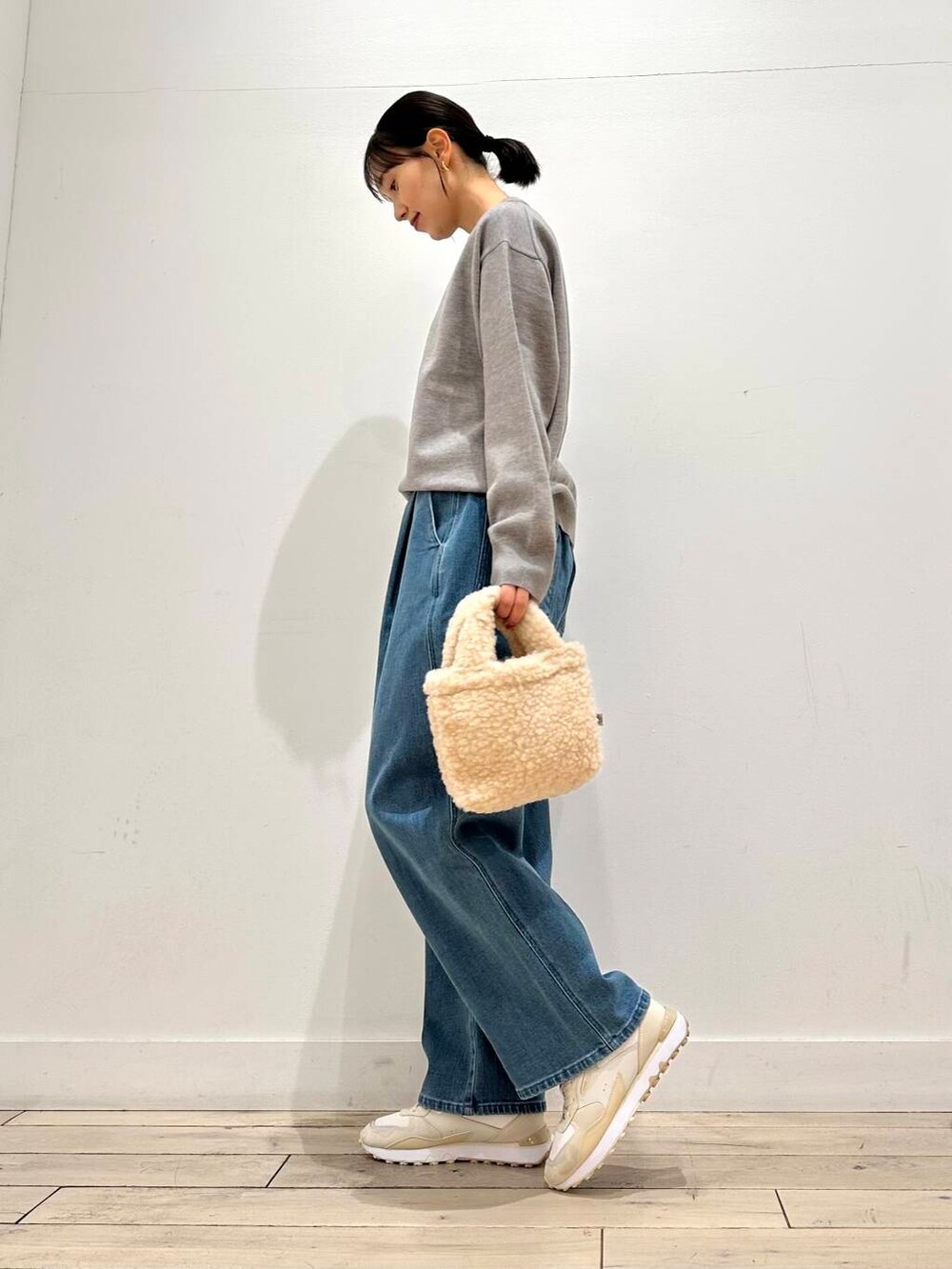 ホワイト系のスニーカー、ブルー系のその他アウター、ベージュ系のハンドバッグを着用したレディースの冬コーディネートの6枚目の写真