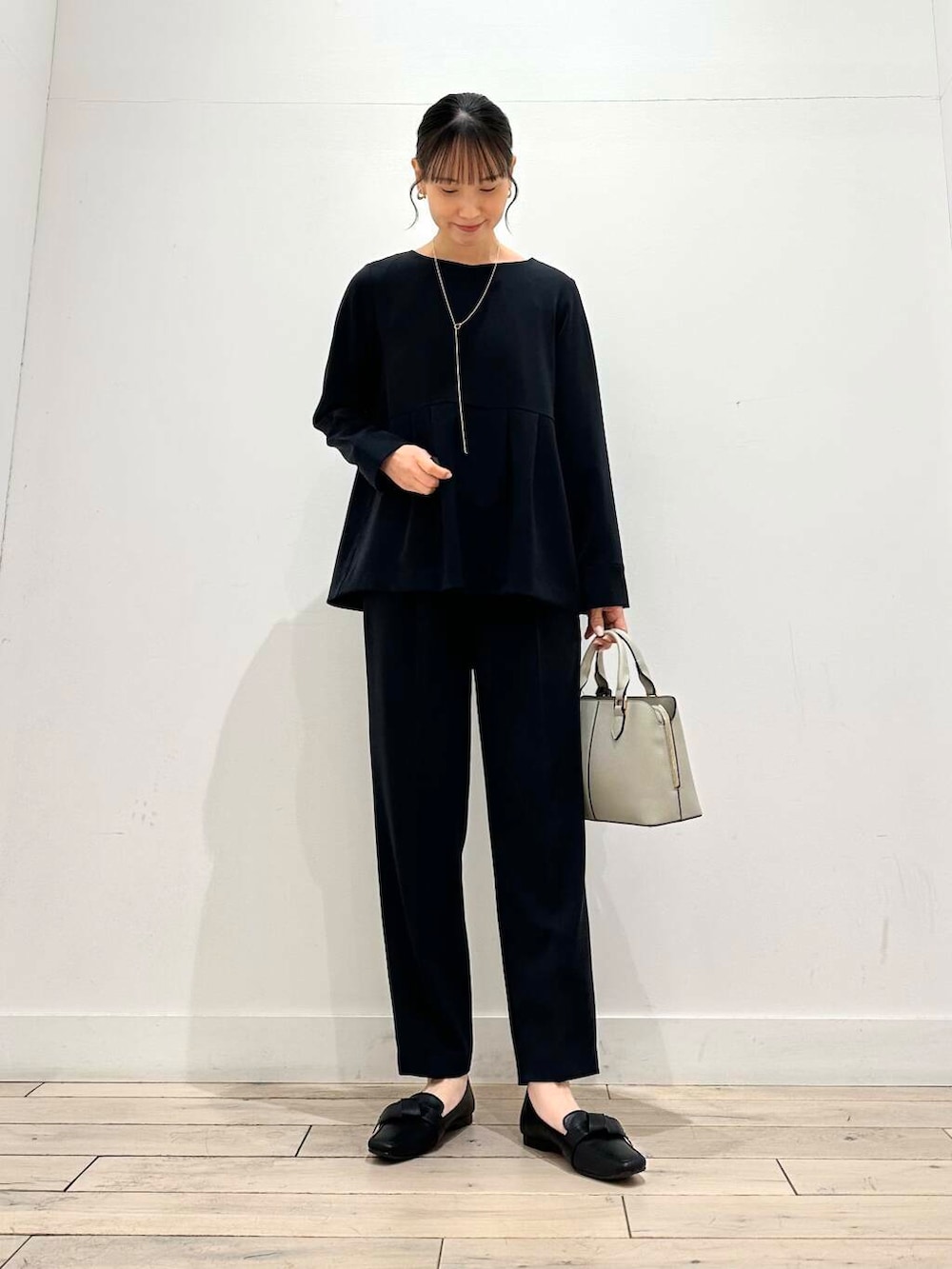 ブラック系のドレスシューズ、グレー系のハンドバッグ、ブルー系のセットアップを着用したレディースの冬コーディネートの4枚目の写真