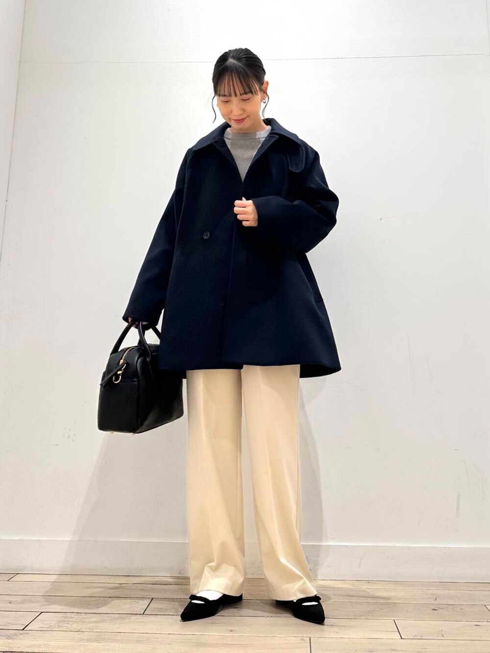 ブラック系のボストンバッグ、ブラック系のパンプス、ブルー系のステンカラーコートを着用したレディースの冬コーディネートの3枚目の写真
