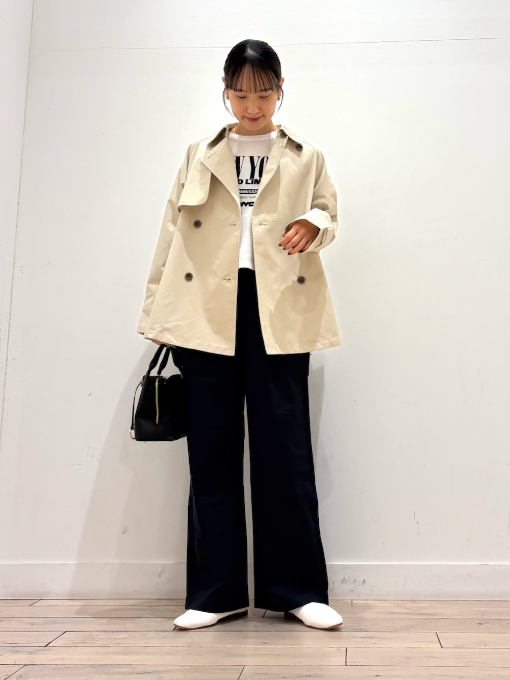 ベージュ系のトレンチコート、ホワイト系のその他シューズ、ブラック系のショルダーバッグを着用したレディースの春コーディネートの2枚目の写真