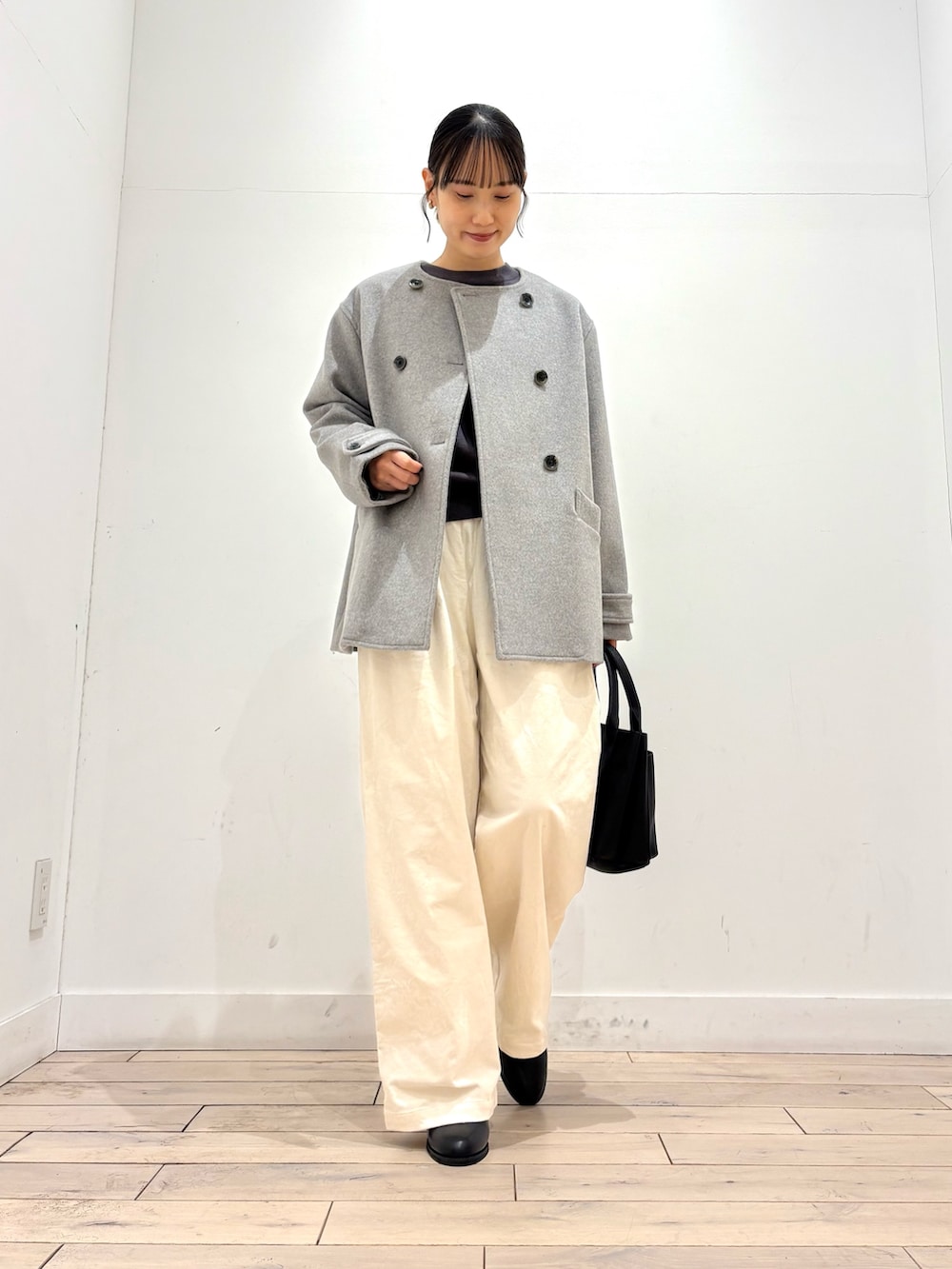 グレー系のピーコート、グレー系のニット/セーター、ブラック系のブーツを着用したレディースの冬コーディネートの2枚目の写真