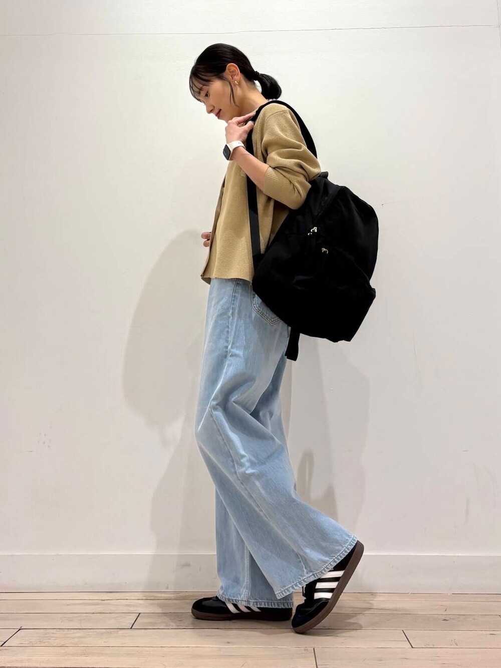 ホワイト系のタンクトップ、ブラック系のバックパック/リュック、ベージュ系のカーディガン/ボレロを着用したレディースの春コーディネートの3枚目の写真
