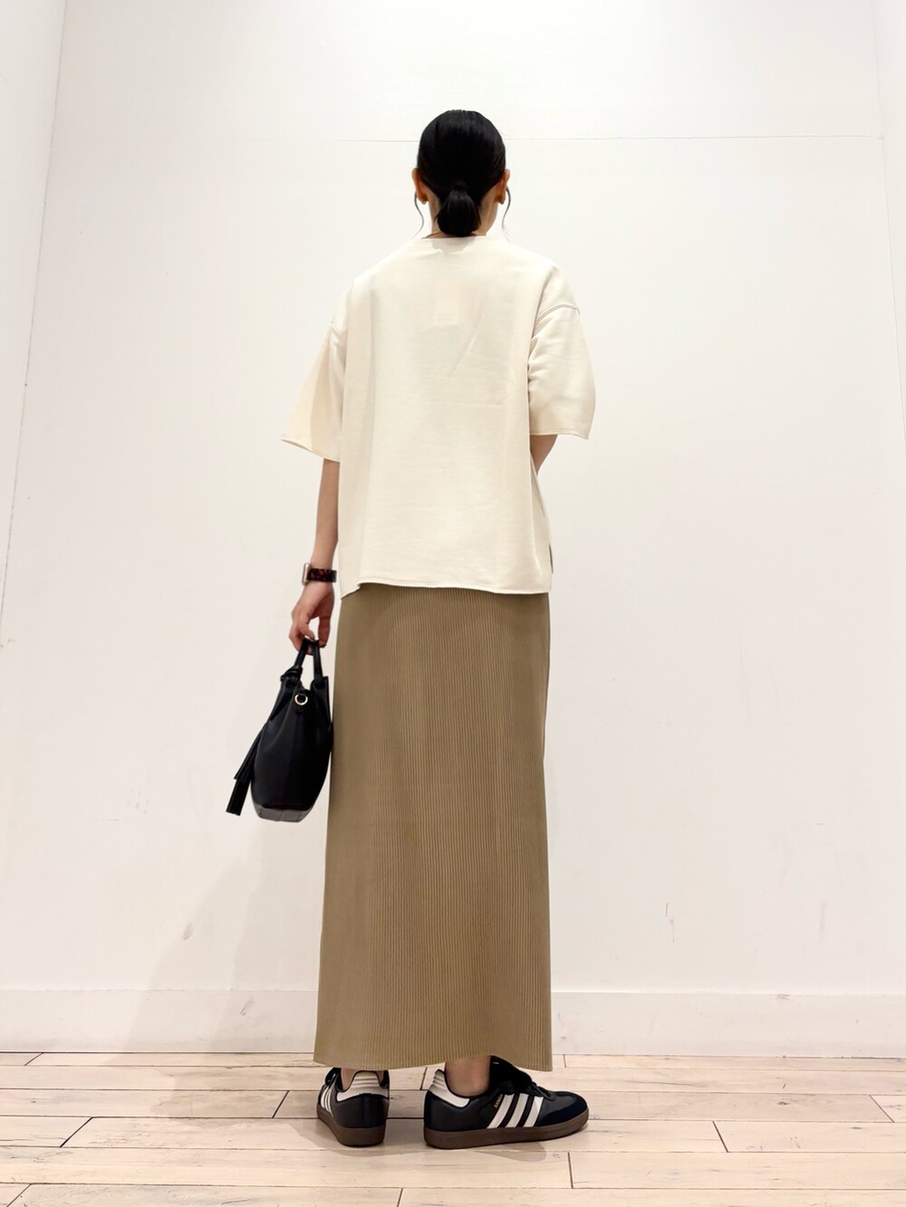 ホワイト系のTシャツ/カットソー、ベージュ系のスカート、ブラック系のスニーカーを着用したレディースの夏コーディネートの3枚目の写真